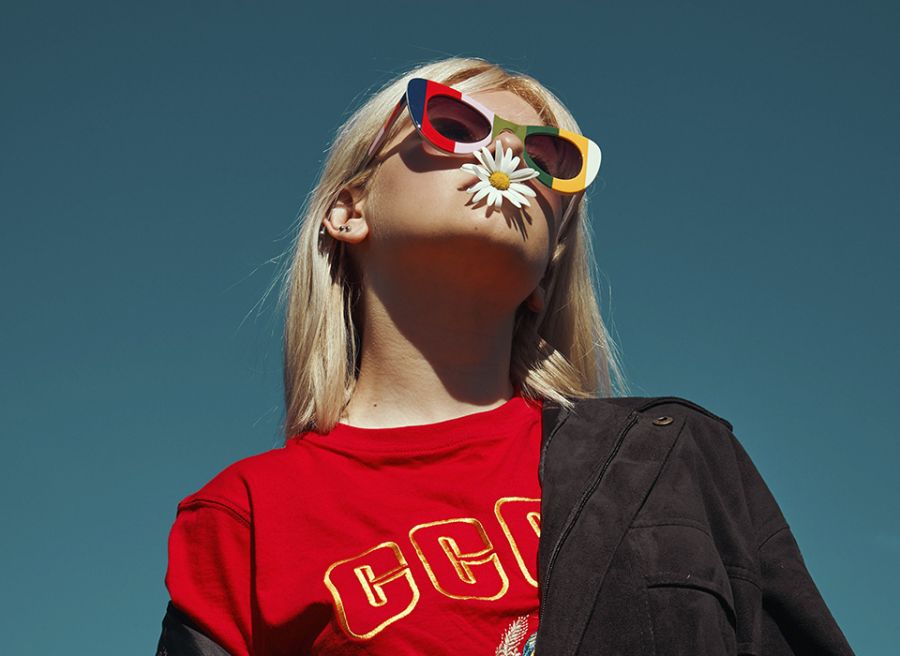 Chica con gafas y una flor en la boca